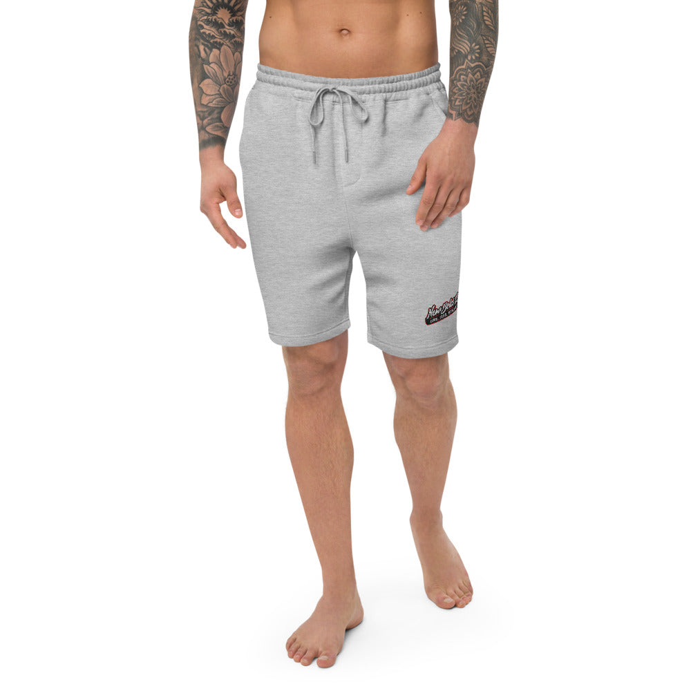 Model wearing a New Bold Life Men's Fleece Shorts - Men's Clothing. Shorts are light grey with Newboldlife logo on lower left leg.