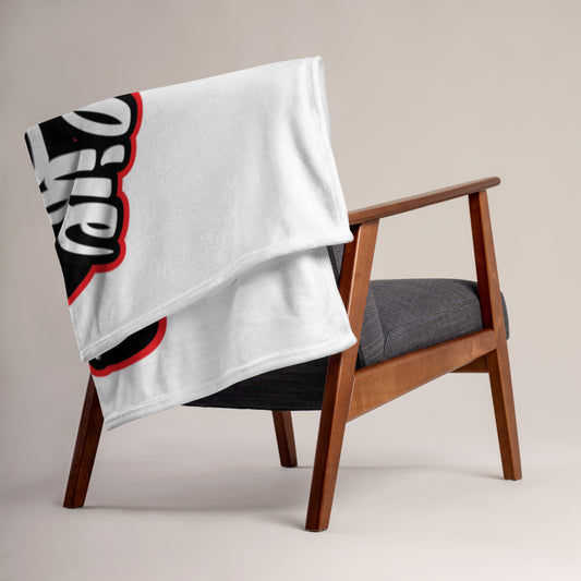 Image of New Bold Life Throw Blanket - Home and Living. Blanket is resting on the back of an arm chair and has a large Newboldlife logo on one side.